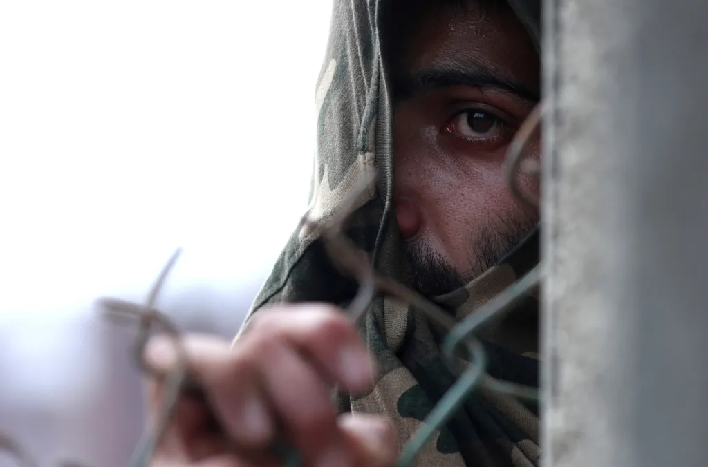 Muž z Kašmíru se kryje za plotem během střetů s indickými bezpečnostními silami. Kašmír v srpnu přišel o svůj zvláštní autonomní status