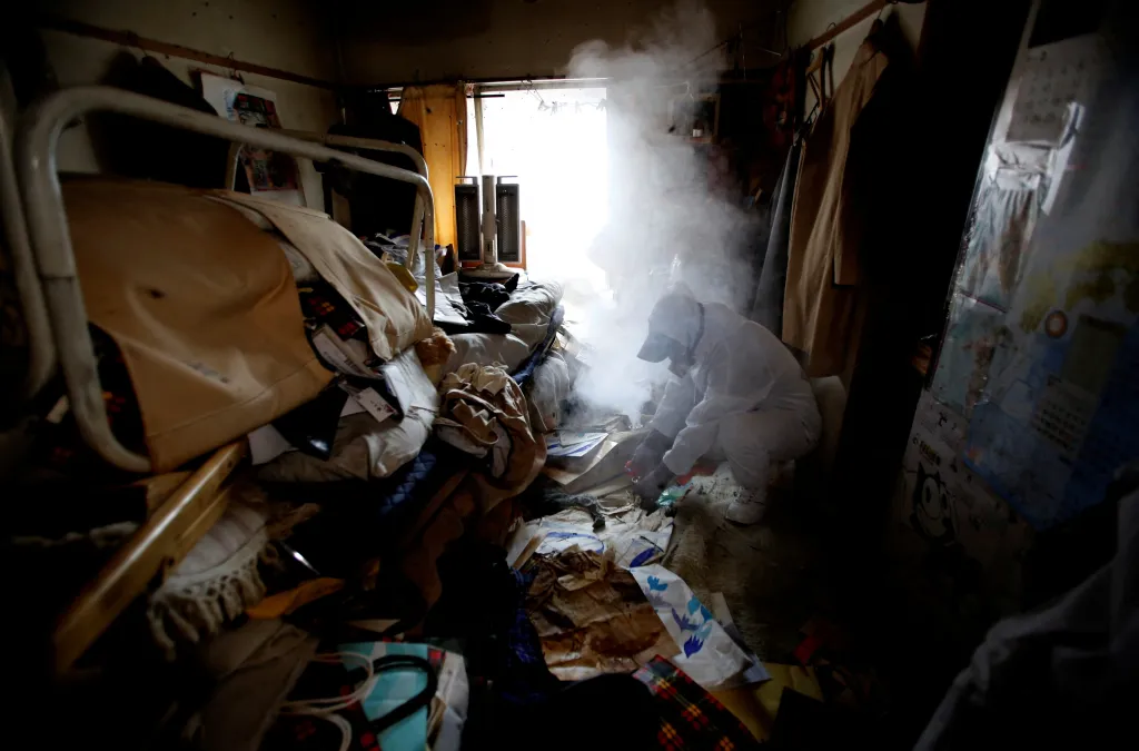 Pracovník speciálního úklidu hubí mouchy v bytě pomocí kouře z insekticidů