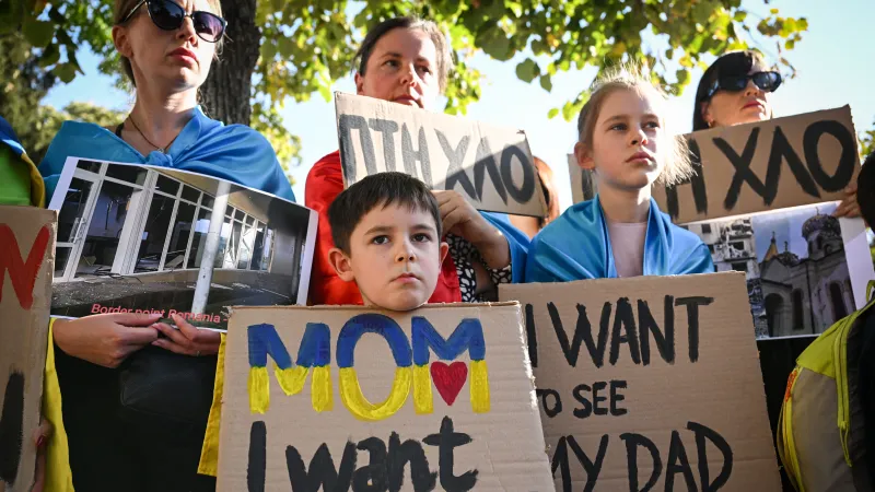 Ukrajinští váleční uprchlíci protestují s transparenty před ruským velvyslanectvím v Rumunsku v Bukurešti 14. října 2023