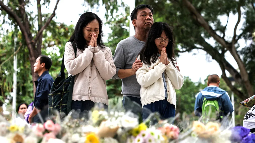 Lidé přicházejí položit květiny a pomodlit se u provizorního památníku u bytového komplexu v Hongkongu