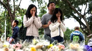 Lidé přicházejí položit květiny a pomodlit se u provizorního památníku u bytového komplexu v Hongkongu