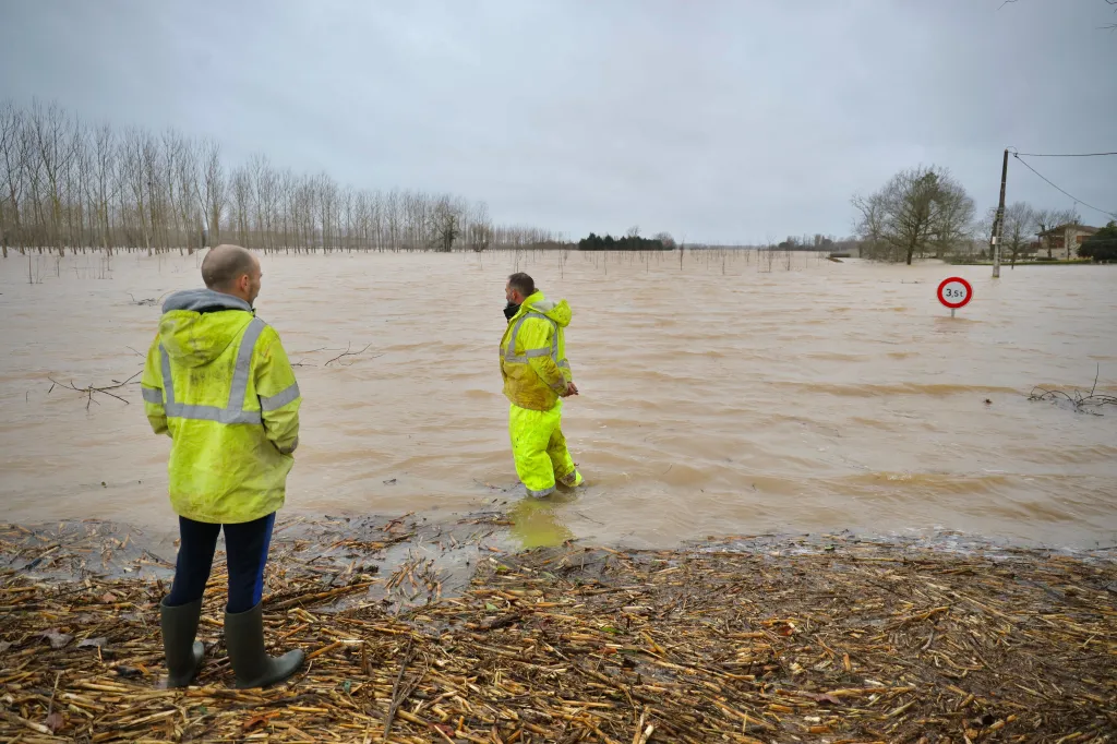 Lidé hledí na zaplavenou silnici u města La Réole na západě Francie