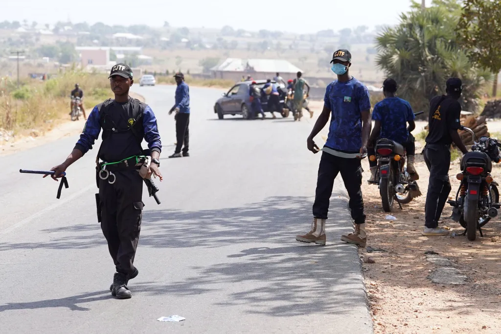 Sodiq Umar, člen Civilní domobrany (CJTF), řídí dopravu, zatímco jeho kolegové pomáhají odtlačit nepojízdný automobil ze silnice