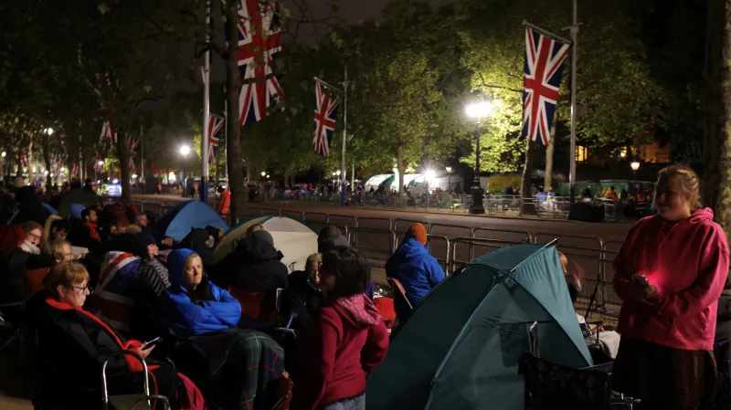 Lidé nocující podél hlavní trasy smutečního průvodu