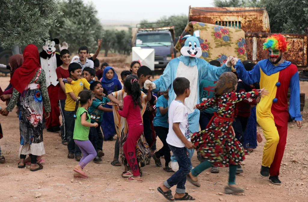 Klauni baví uprchlé syrské děti první den po ramadánu v olivovém háji na severu města Idlíb