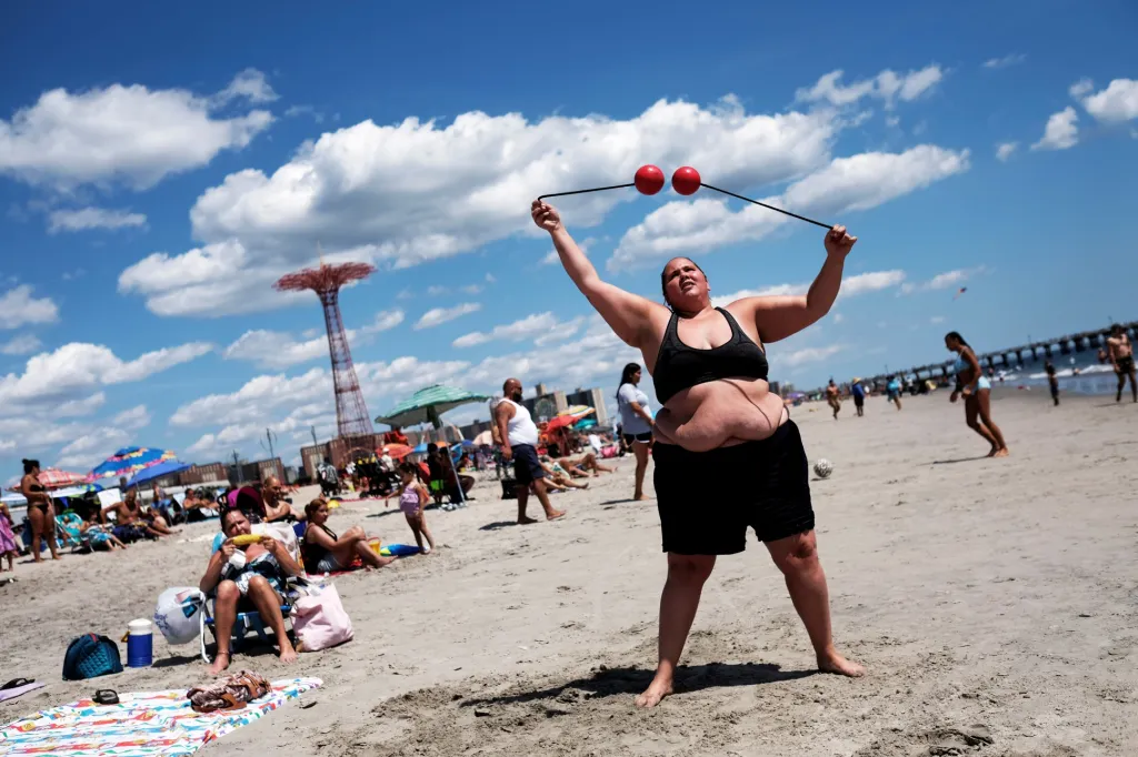 Běžný den na Coney Island Beach. Yenne (27 let) cvičí s žonglerskými pomůckami na pláži