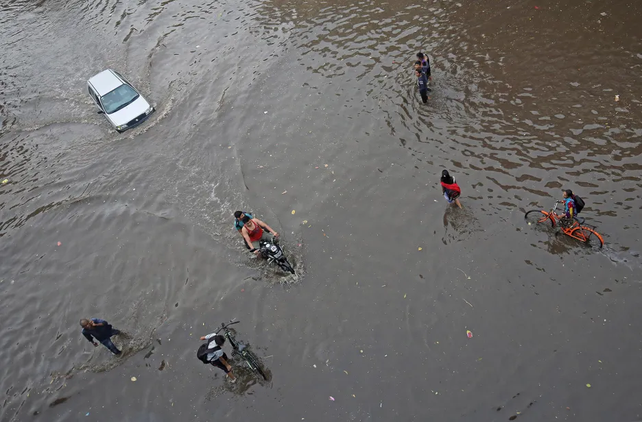 Lidé se brouzdají zaplavenou silnicí po těžkých deštích v indickém Ahmadabádu