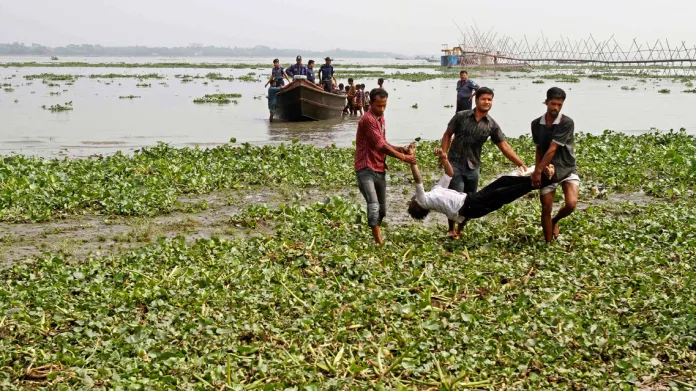 Záchranáři odnášejí oběť lodního neštěstí v Bangladéši
