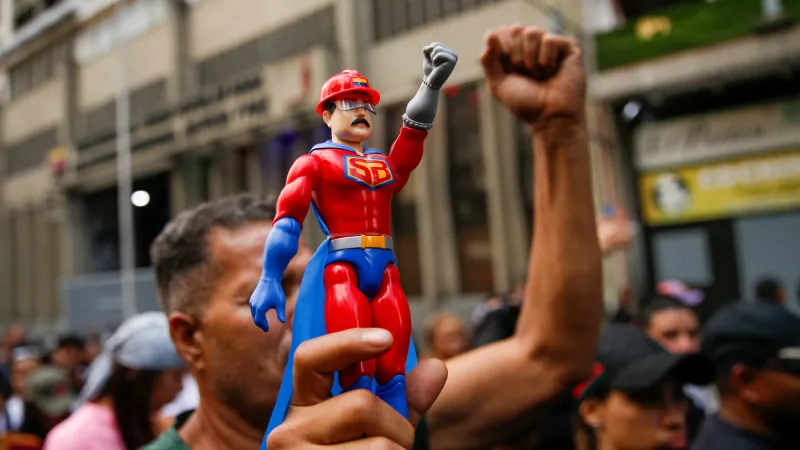Účastník pochodu drží figurku prezidenta Nicoláse Madura v obleku superhrdiny