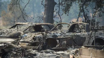 Zničená auta a domy na silnici Wolf Creek. Tisíce obyvatel již byly nuceny v pondělí opustit svá obydlí. Kalifornie se obává řady dalších katastrofických požárů podobně jako minulý rok