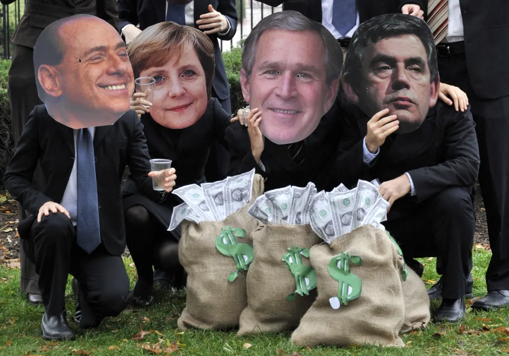 Protestující v maskách italského premiéra Silvia Berlusconiho, německé kancléřky Angely Merkelové, amerického prezidenta George W. Bushe a britského premiéra Gordona Browna během protestu před Bílým domem ve Washingtonu v listopadu 2008. Vedoucí představitelé států a vlád skupiny G20 se sešli v Bílém domě, aby projednali důsledky globální finanční krize