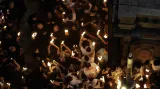 Křesťanští poutníci drží svíčky v Chrámu Božího hrobu