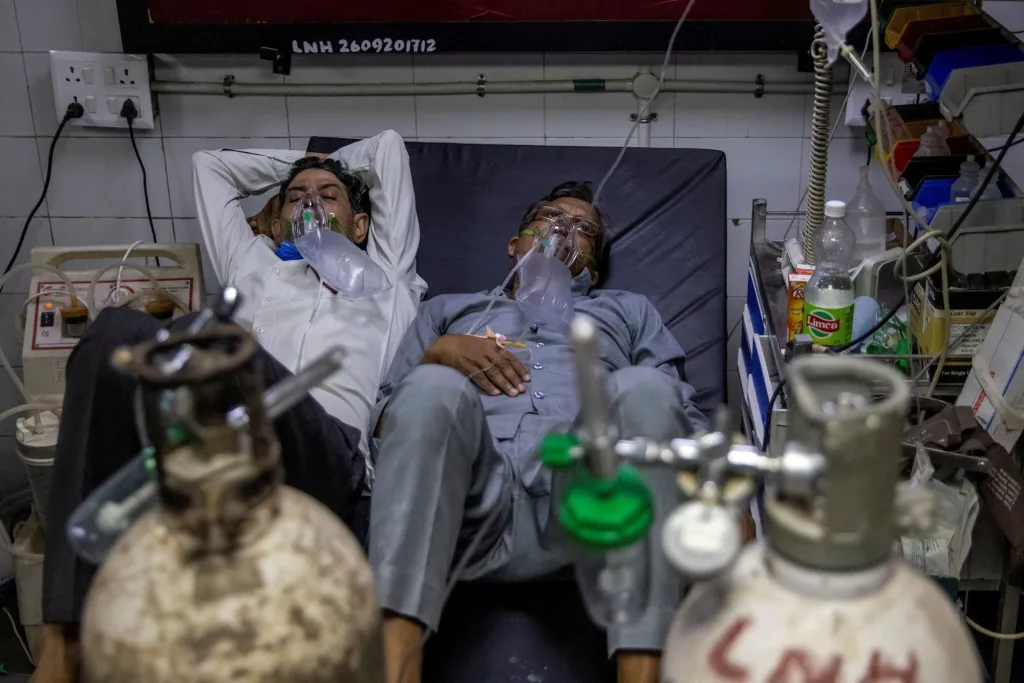 Pacienti trpící koronavirem se kvůli přetíženým nemocnicím při léčbě musí dělit o jedno lůžko. Nové Dillí, Indie, 2020