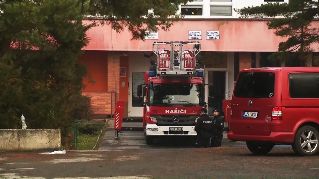 Hasičské auto stojící před církevní školou, která sousedí se střední školou, v níž hořelo