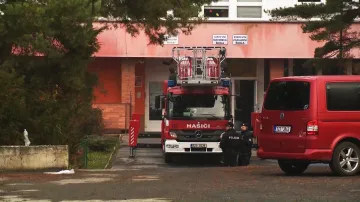 Hasičské auto stojící před církevní školou, která sousedí se střední školou, v níž hořelo