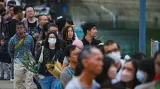 Lidé čekají ve frontě, aby položili květiny u provizorního památníku a vzdali hold obětem smrtelného požáru bytového komplexu v Hongkongu