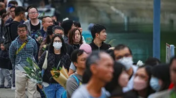 Lidé čekají ve frontě, aby položili květiny u provizorního památníku a vzdali hold obětem smrtelného požáru bytového komplexu v Hongkongu