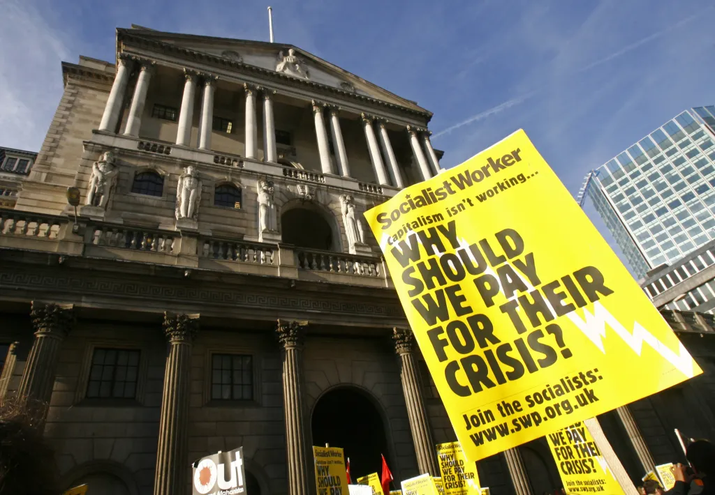 Demonstrace před Bank of England (centrální banka Velké Británie) v říjnu 2008 a transparent s nápisem „Proč bychom měli platit za jejich krizi?“