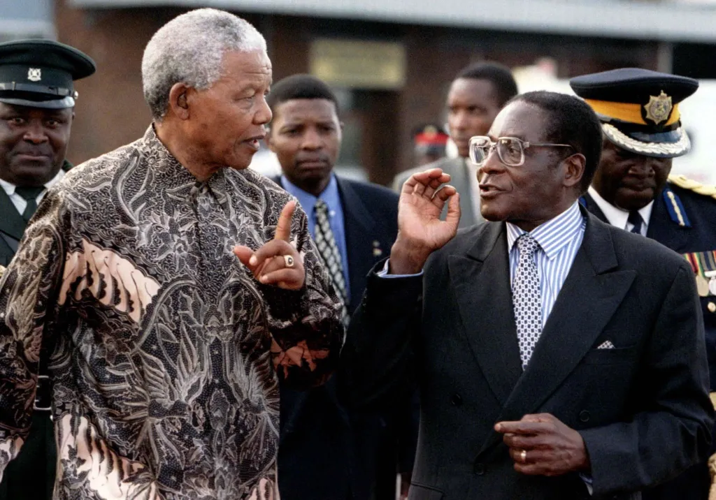Prezident Nelson Mandela z Jihoafrické republiky a Robert Mugabe ze Zimbabwe spolu hovoří 21. května 1997 při odjezdu ze země po třídenní státní návštěvě. Mandela otevřel Světové ekonomické fórum v jihoafrickém regionu s cílem zlepšit investice a obchod