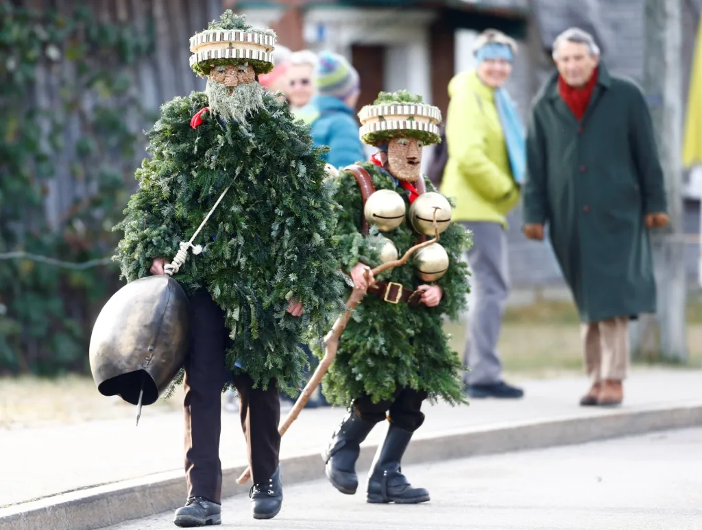 Muži oblečení v kostýmu postaviček "Chlaeuse"putují vesnicí Urnaesch ve Švýcarsku