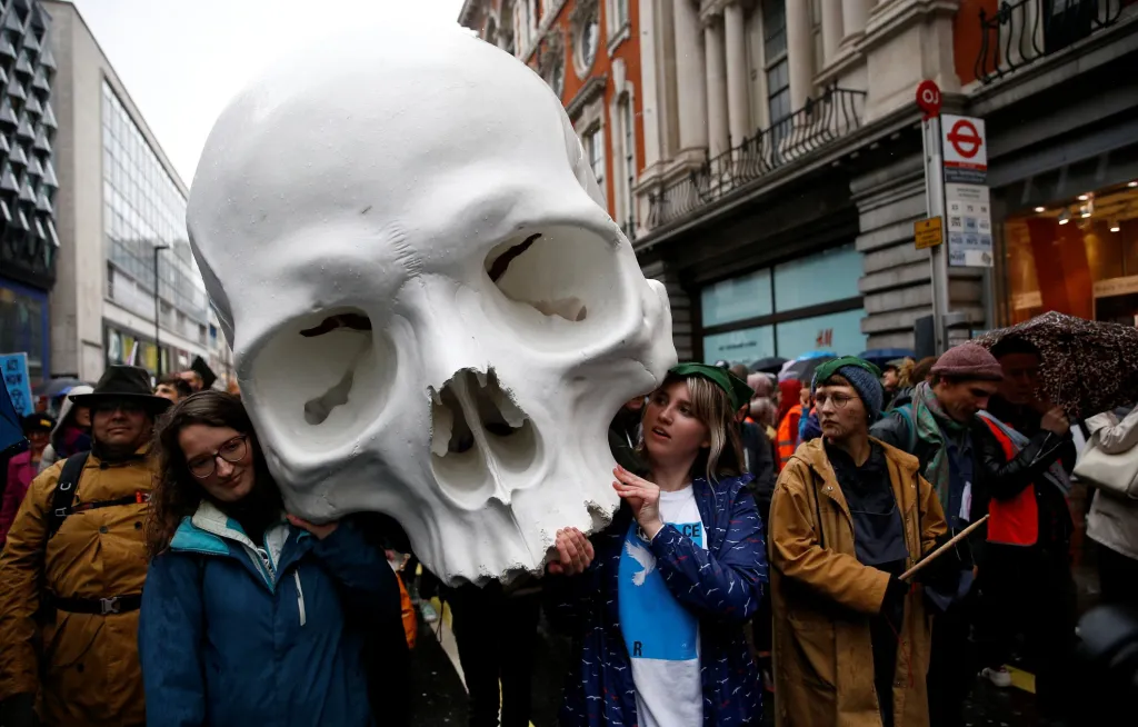 Klimatičtí aktivisté si během demonstrace v Londýně nesou obří lidskou lebku