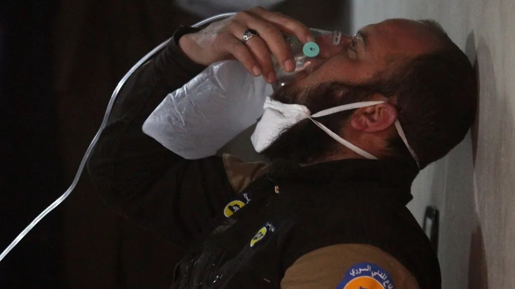 Příslušník civilní obrany používá po útoku armády v Chán Šajchún kyslíkovou masku