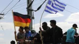 Migranti s německou a řeckou vlajkou
