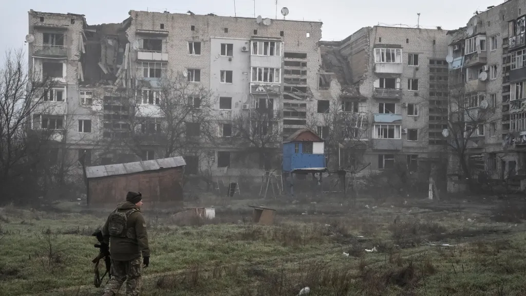 Ukrajinský voják poblíž obytných budov poškozených ruskými údery ve městě Orichiv v Záporožské oblasti
