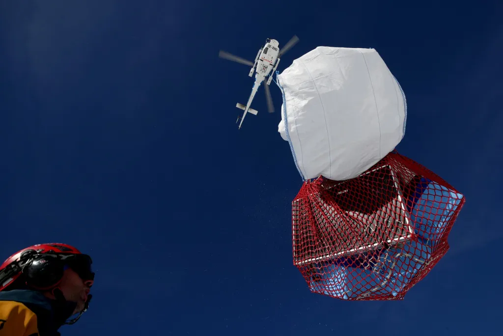 Navaděč ukazuje vrtulníku, kde má položit náklad s vybavením po vrtání ledu na ledovci Gepatschferner. Vědci zde hledají nejstarší rakouský led na vrcholku Weissseespitze