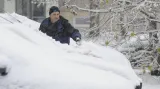 Řidič odklízí sníh z auta
