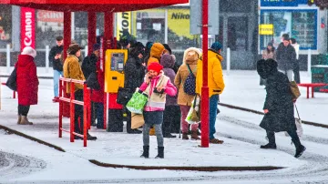 Lidé v chumelenici čekají na trolejbusové zastávce na Mendlově náměstí v Brně