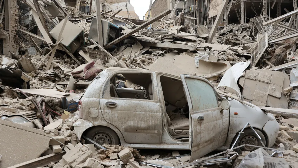 Zničené auto a trosky budovy po útoku v Teheránu