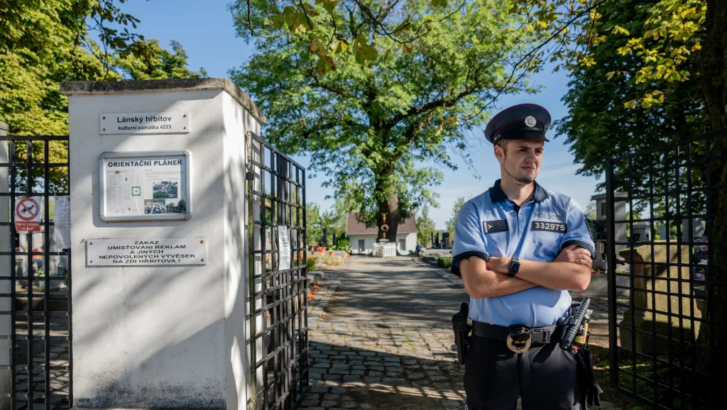 Policista stojí před hřbitovem v Lánech, kde odborníci exhumují z rodinné hrobky ostatky někdejšího ministra zahraničí Jana Masaryka (2. září 2026)
