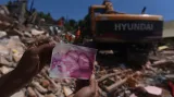 Obyvatel postižené oblasti ukazuje na fotografiích pohřešované příbuzné po silném zemětřesení na ostrově Lombok