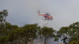 Vrtulník shazuje vodu na hořící les v Penrose