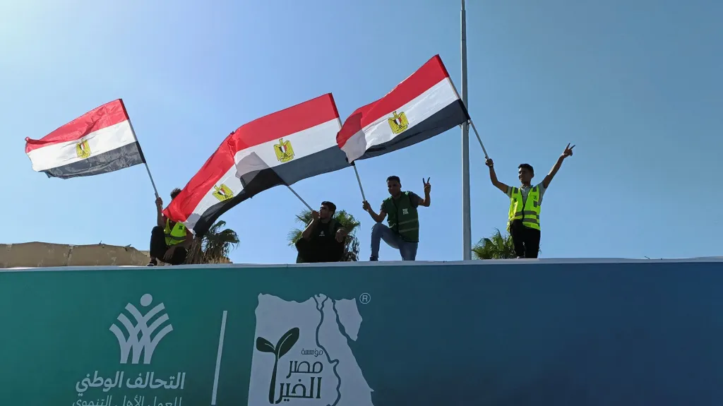 Lidé s egyptskými vlajkami povzbuzují kamion, který převáží humanitární pomoc pro Palestince od egyptských nevládních organizací