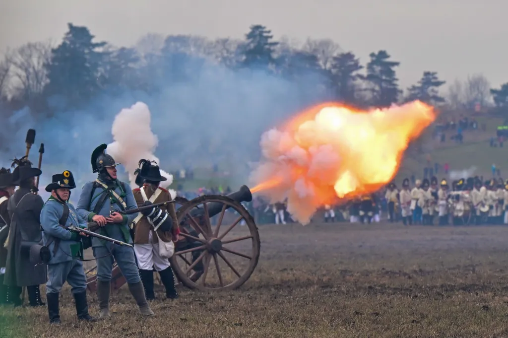 Nadšenci v historických uniformách z napoleonských dob při palbě z kanónu