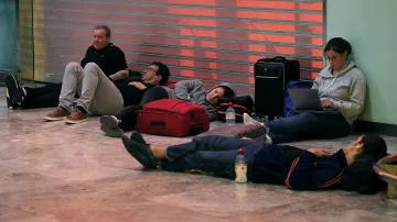 Uvízlí cestující čekají na podlaze příletové haly na letišti v Alicante