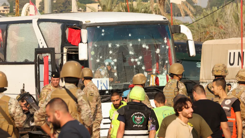 Lidé stojí u poškozeného autobusu OSN po izraelském útoku u vjezdu do města Sajdá