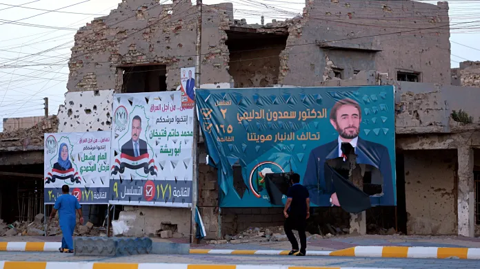 Volební billboardy posazené mezi ruiny domů. Iráčané volí nový parlament