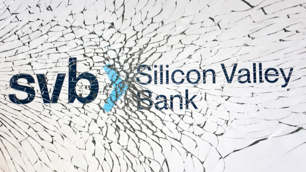Ilustrace loga Silicon Valley Bank viděného skrze rozbité sklo