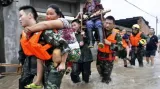 Čínští záchranáři odnášejí lidi zasažené povodněmi