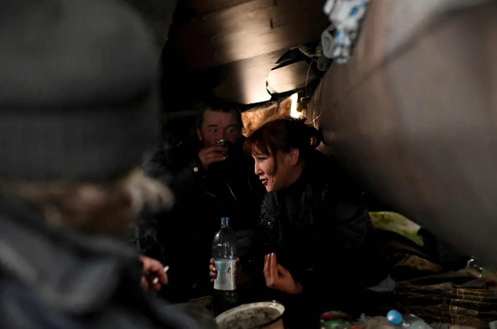 Bezdomovci Alexej, Andrej  a Galija si ve svém úkrytu dopřávají alkoholický míchaný nápoj