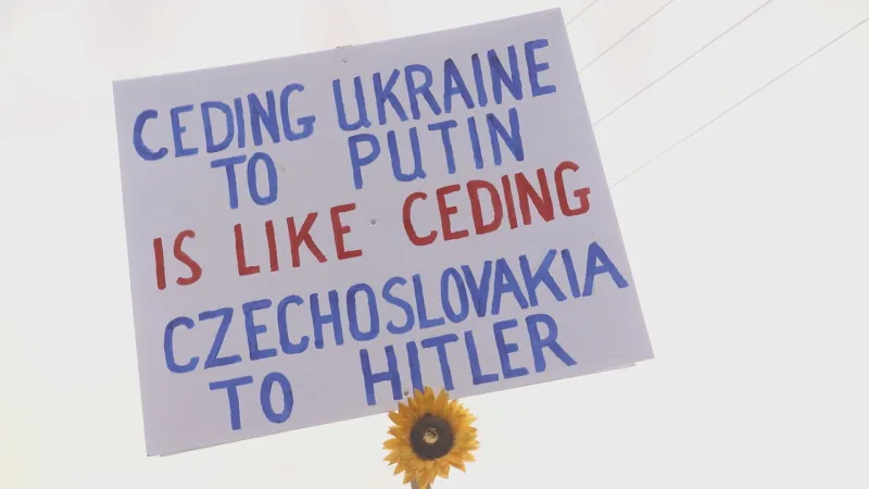Transparent s nápisem „Přenechat Ukrajinu Putinovi je jako přenechat Československo Hitlerovi“