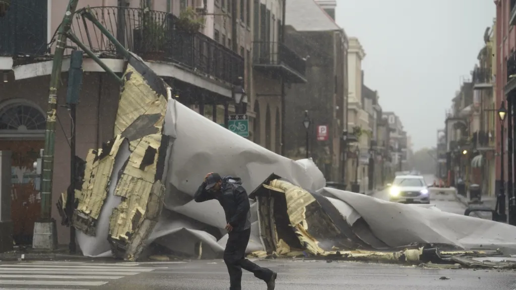 Muž prochází ve Francouzské čtvrti města New Orleans kolem stržené střechy