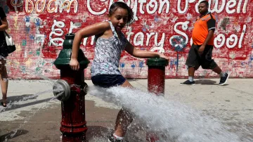 Dívka využívá ke zchlazení vodu z otevřeného požárního hydrantu