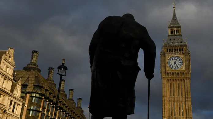 Socha Winstona Churchilla na londýnském Parliament Square s budovami parlamentu a Elizabeth Tower, běžněji známou jako Big Ben