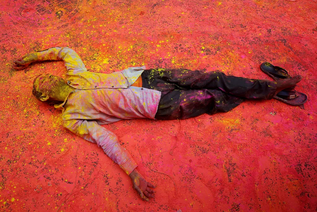 Účastník hinduistického festivalu Holi potřísněný barevným práškem při odpočinku na ulici indické Kalkaty