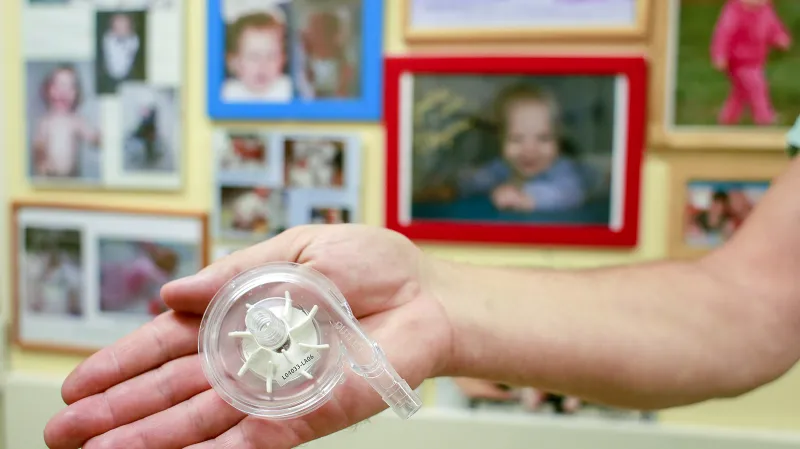 Klíčová součástka mimotělní pumpy. Rotor, který zajišťuje přívod kyslíku do krve pacienta. V pozadí fotografie několika z mnoha set dětských pacientů, kterým toto oddělení, a některým i tento přístroj, zachránilo život.