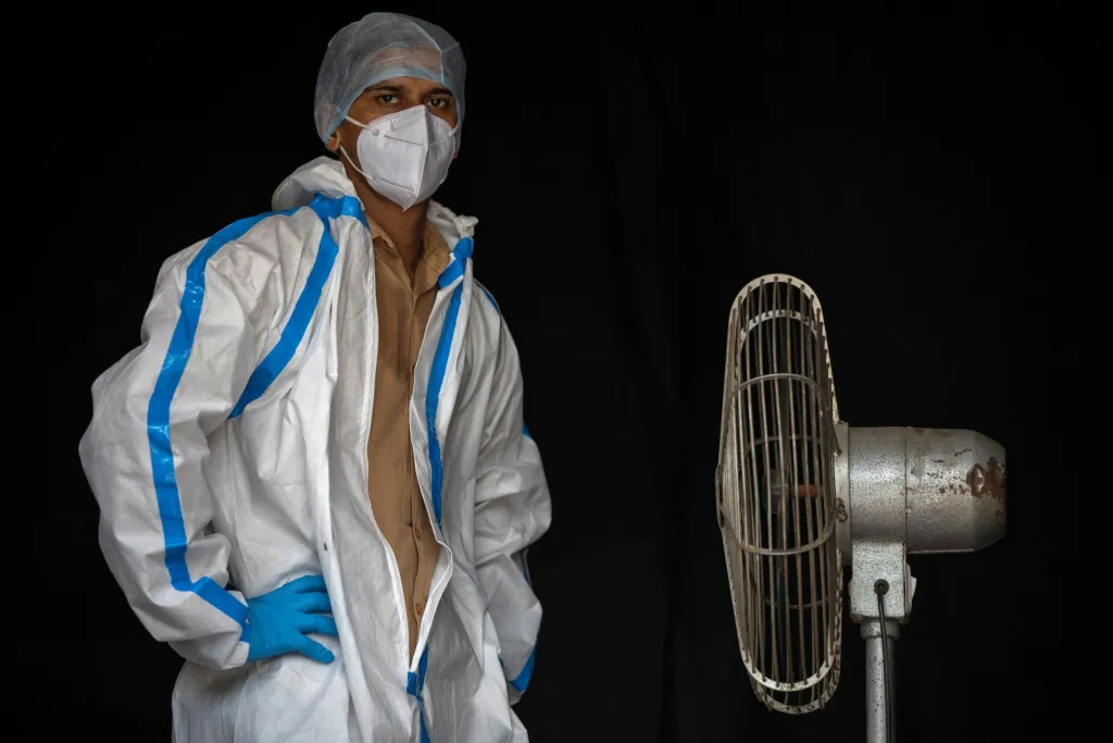 Zdravotnický pracovník si alespoň na chvíli rozepnul ochranný oblek a chladí se během pauzy při práci. Od pacientů sbírá vzorky k testům na koronavirus. Nové Dillí, Indie, 2020